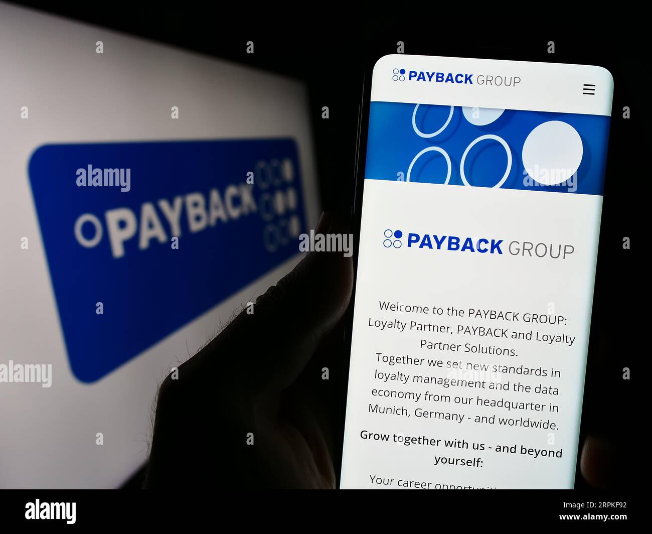 Persona che possiede uno smartphone con il sito Web della società tedesca di gestione della fidelizzazione Payback GmbH sullo schermo con logo. Concentrarsi sul centro del display del telefono. Foto Stock