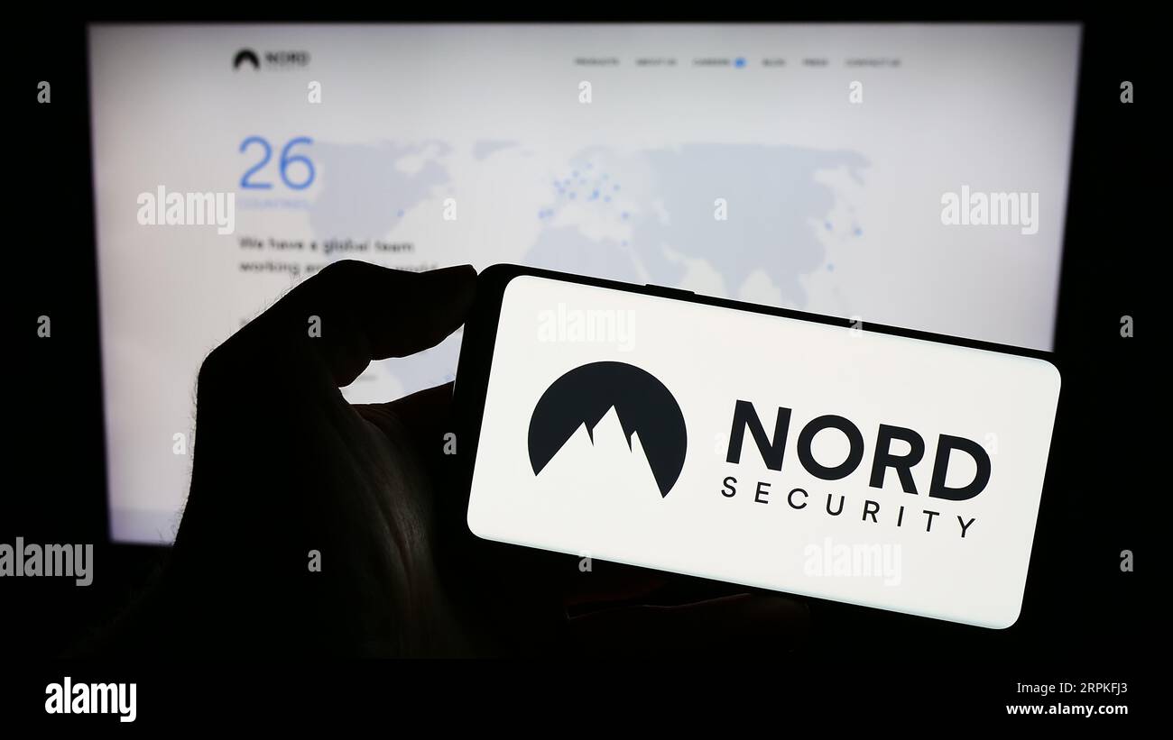 Persona che possiede un telefono cellulare con il logo della società di accesso VPN Nordsec Ltd. Sullo schermo davanti alla pagina Web aziendale. Concentrarsi sul display del telefono. Foto Stock