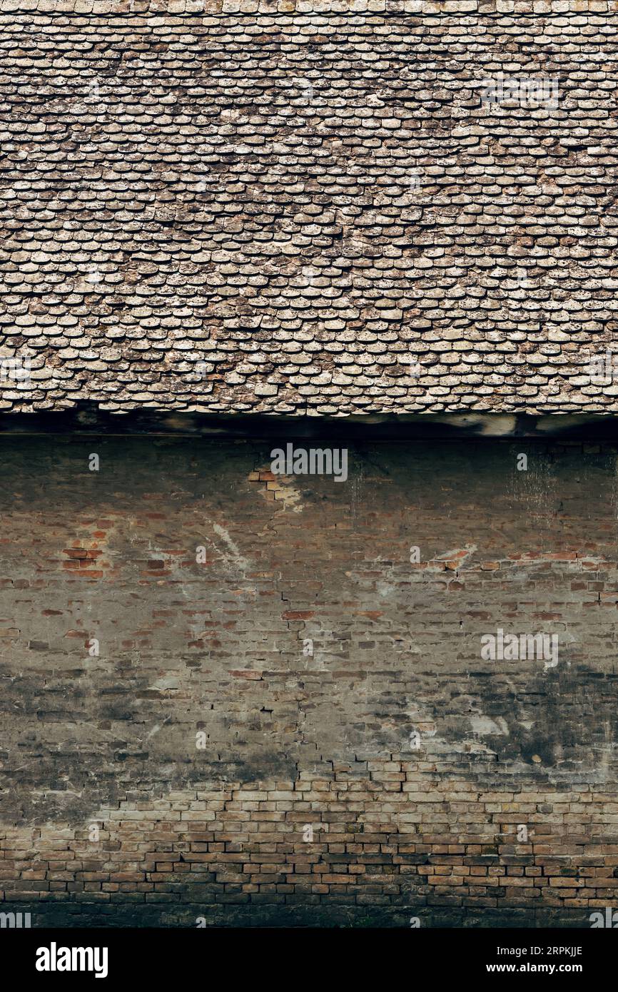 Vecchia casa abbandonata con pareti in mattoni danneggiate e tegole usurate come sfondo Foto Stock