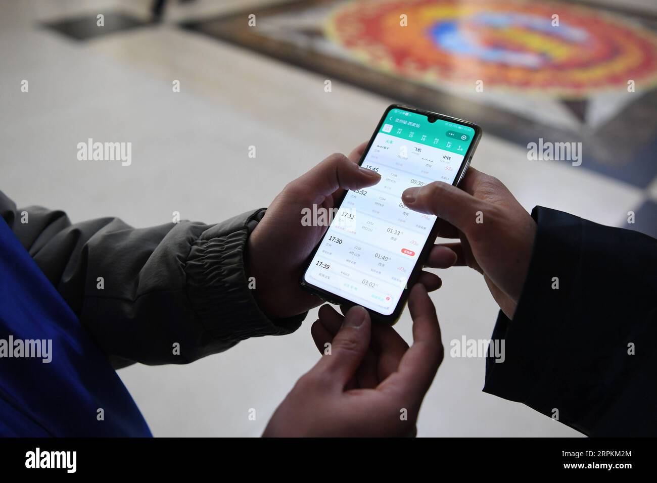 200113 -- LANZHOU, 13 gennaio 2020 -- Un volontario aiuta un passeggero a controllare le informazioni del treno alla stazione ferroviaria di Lanzhou, capitale della provincia del Gansu della Cina nord-occidentale, 13 gennaio 2020. Durante la corsa al Festival di Primavera, la stazione ferroviaria di Lanzhou e la stazione ferroviaria di Lanzhou West realizzano un servizio volontario speciale chiamato Steward of the Journey . Per i passeggeri che hanno preso degli appuntamenti, che hanno fretta di salire sui treni o che non hanno familiarità con il sistema di biglietteria mobile, i volontari sono a disposizione per fornire il servizio e aiutarli a ridurre i tempi di salita sui treni, portando i passeggeri c Foto Stock