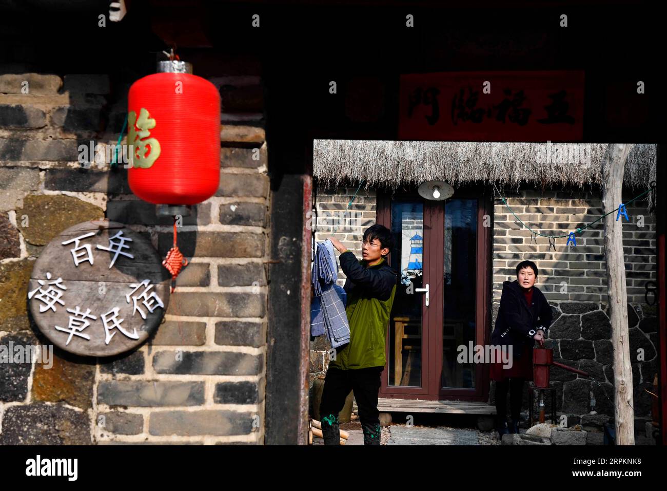 200115 -- RONGCHENG, 15 gennaio 2020 -- Yu Haiyang e sua madre lavorano nel loro cortile nel villaggio di Yandunjiao di Rongcheng, provincia dello Shandong della Cina orientale, 12 gennaio 2020. Yandunjiao, un villaggio costiero nello Shandong, è pieno di vitalità come molti cigni invernali qui. Alla fine del 2014, è stato lanciato il servizio di treno ad alta velocità tra Qingdao e Rongcheng e numerosi turisti sono venuti qui per vedere i cigni, assaggiare le prelibatezze locali e vivere la famiglia in case con tetto di alghe. Yu Haiyang, un abitante del villaggio nativo che una volta lavorava a Singapore dopo la laurea, tornò nella città natale e iniziò un'attività in famiglia Foto Stock