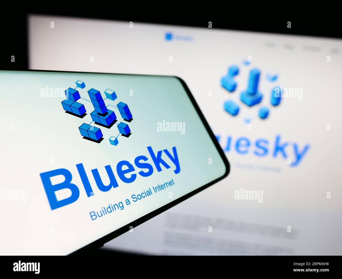 Cellulare con logo dell'iniziativa di social network Bluesky sullo schermo di fronte al sito web. Mettere a fuoco il display centrale sinistro del telefono. Foto Stock