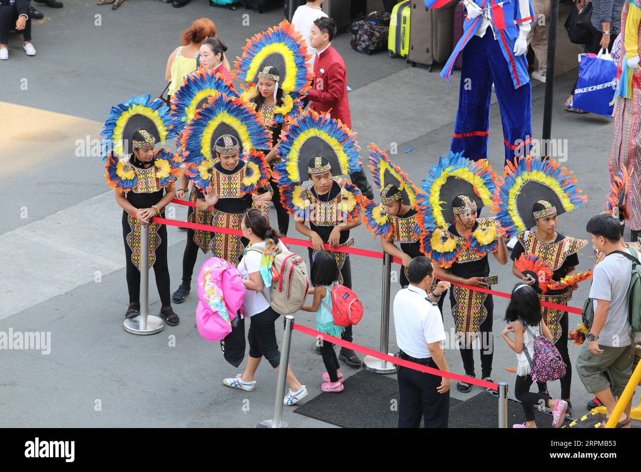 Festa di benvenuto a tema festa filippina per la nave da crociera al molo di Manila: Musicisti con strumenti di bambù, ballerini filippini, Higantes, bandiere Foto Stock