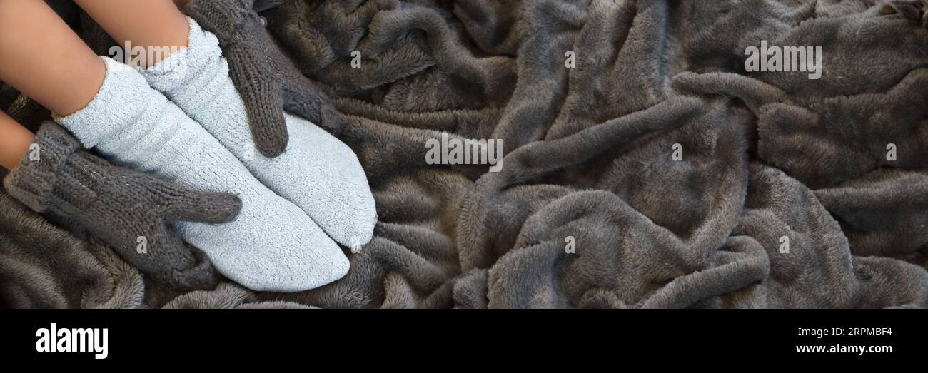 Piedi in comode e calde calze di lana su una coperta, testata invernale panoramica Foto Stock