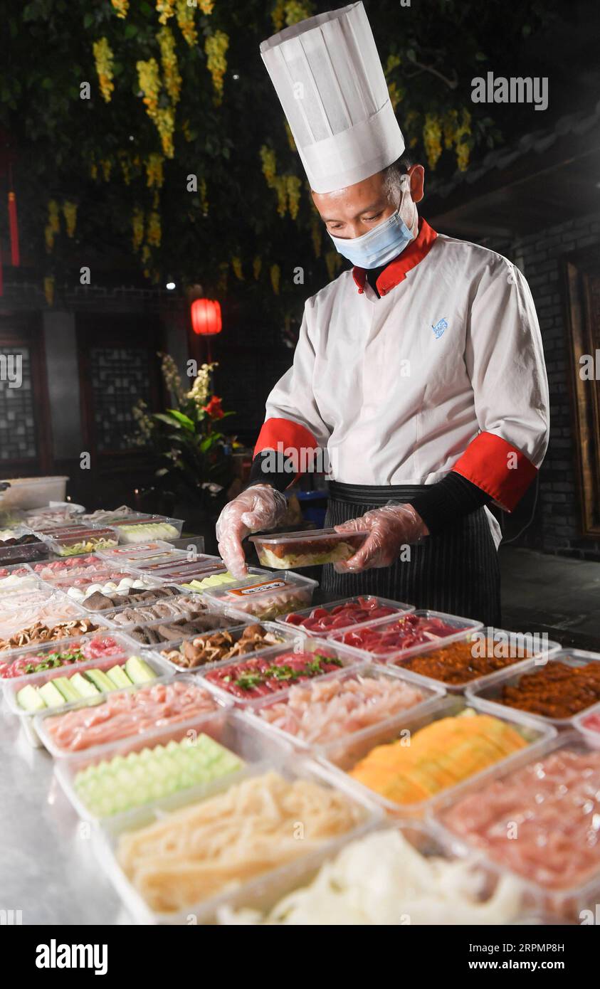 200215 -- CHONGQING, 15 febbraio 2020 -- Un membro dello staff di un ristorante di hot pot prepara cibo da asporto nel comune di Chongqing della Cina sud-occidentale, 15 febbraio 2020. Per la prevenzione e il controllo della nuova polmonite da coronavirus, alcuni ristoranti di pentole calde a Chongqing, sotto la guida della Commissione per il commercio municipale di Chongqing e dei servizi competenti, forniscono ai consumatori un servizio di asporto di pentole calde a contatto zero. I consumatori possono ordinare cibo attraverso varie piattaforme come il telefono, WeChat e Internet. I servizi di prelievo sono stati rafforzati in termini di sicurezza di acquisto, lavorazione e consegna, winn Foto Stock