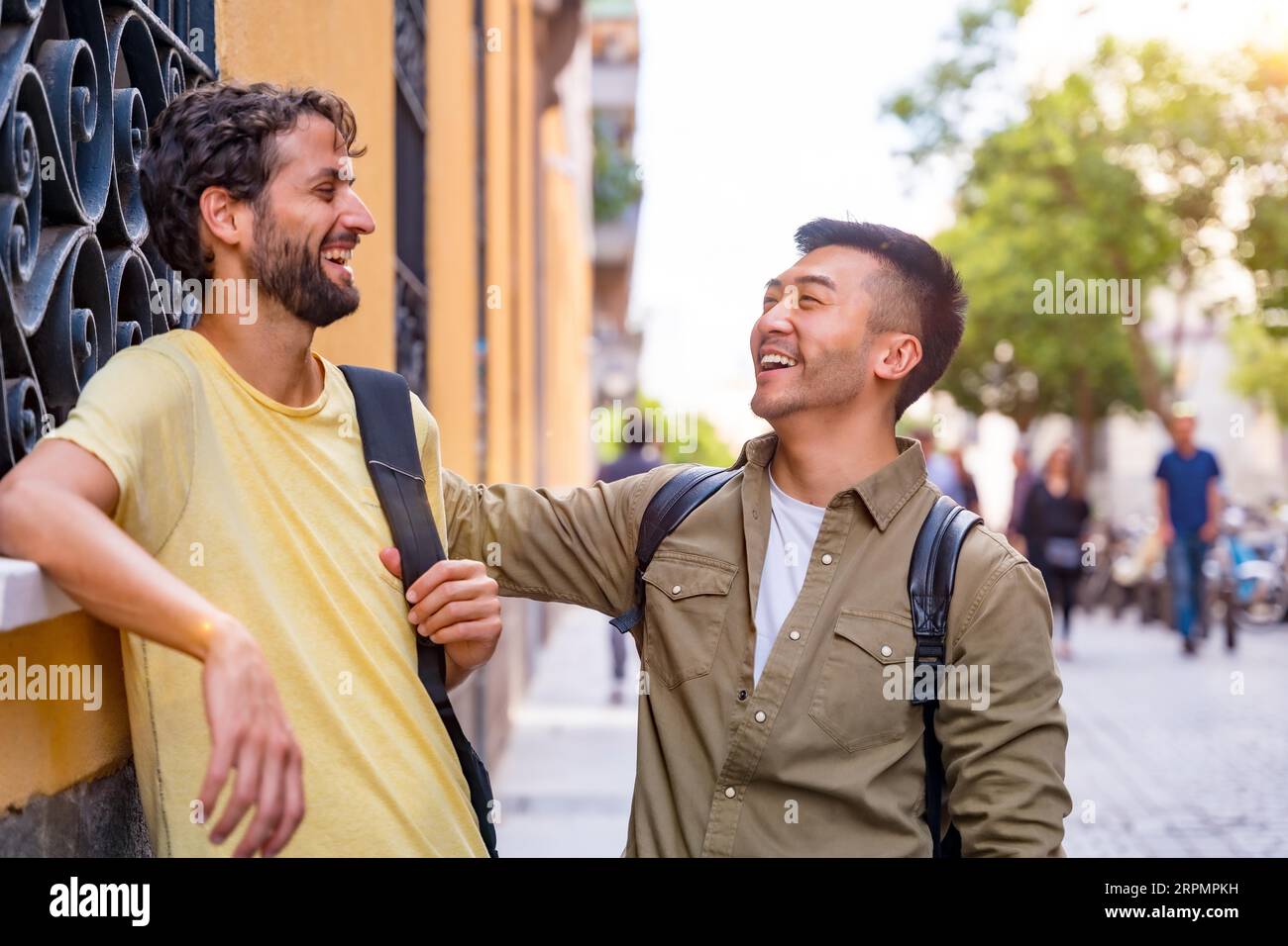 Due amici maschili multietnici del college in città sorridenti, asiatico e caucasico Foto Stock