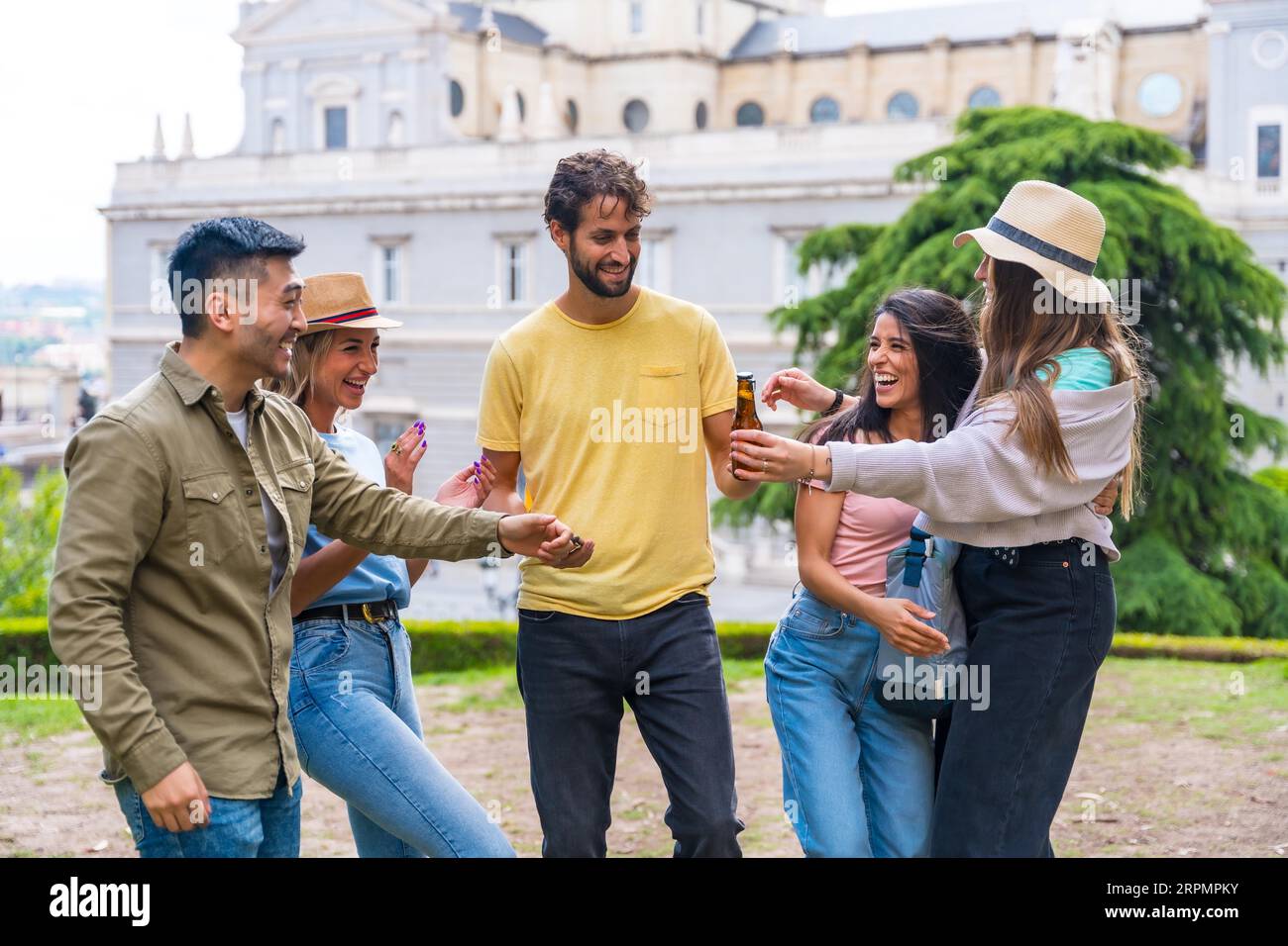Gruppo multietnico di amici che festeggiano in un parco cittadino con birre. divertimento estivo, saluti al nuovo amico che è arrivato Foto Stock