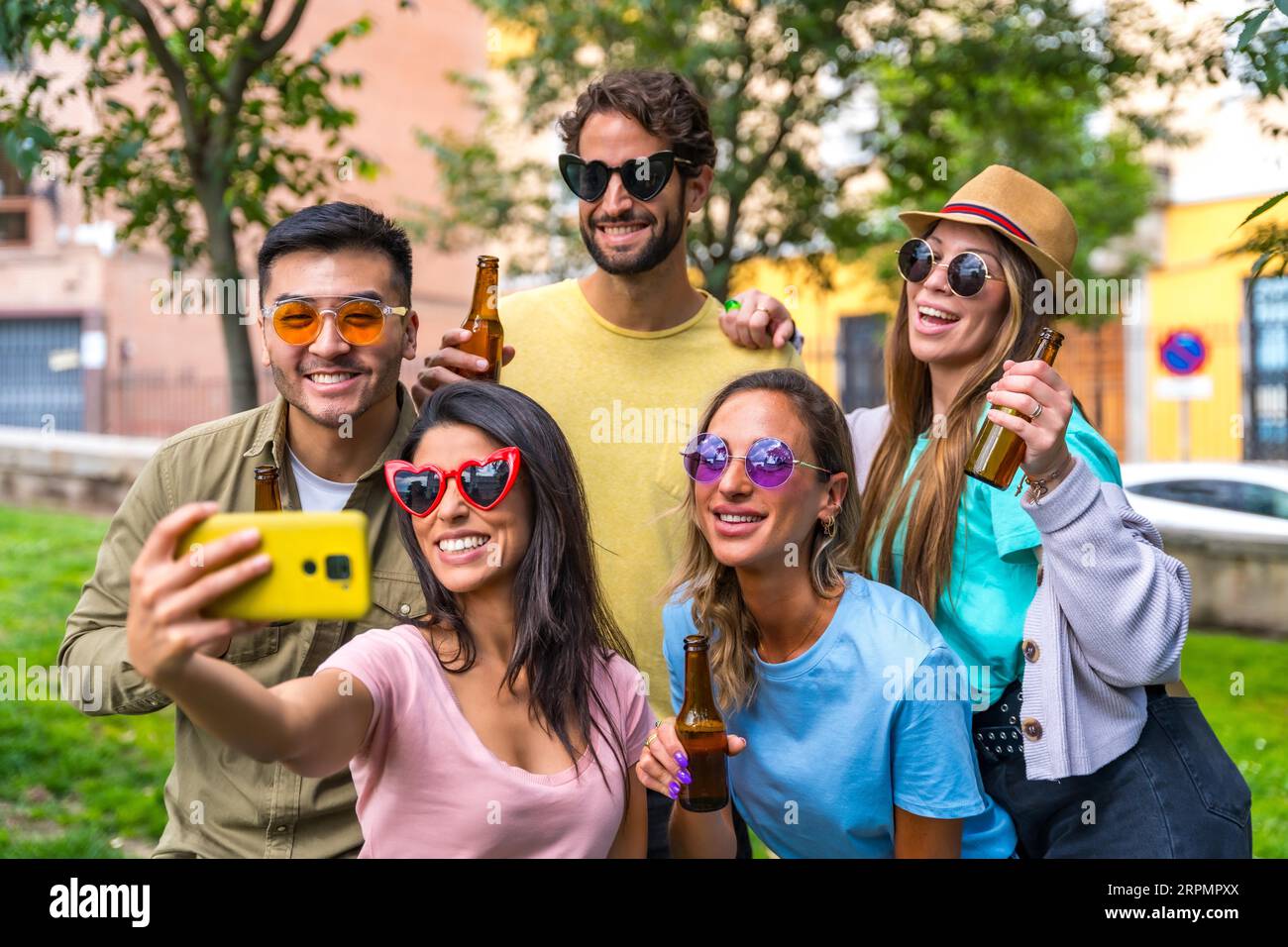 Gruppo multietnico di amici che festeggiano nel parco cittadino scattando un selfie, un concetto di amicizia e divertimento con gli occhiali da sole Foto Stock