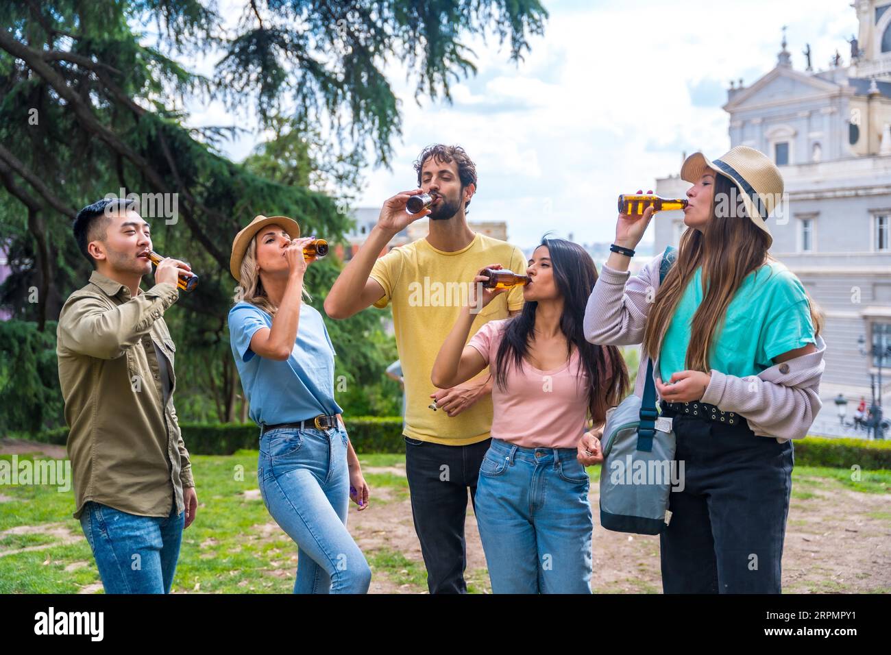 Gruppo multietnico di amici che festeggiano in un parco cittadino con birre. Amici che bevono birra fredda Foto Stock