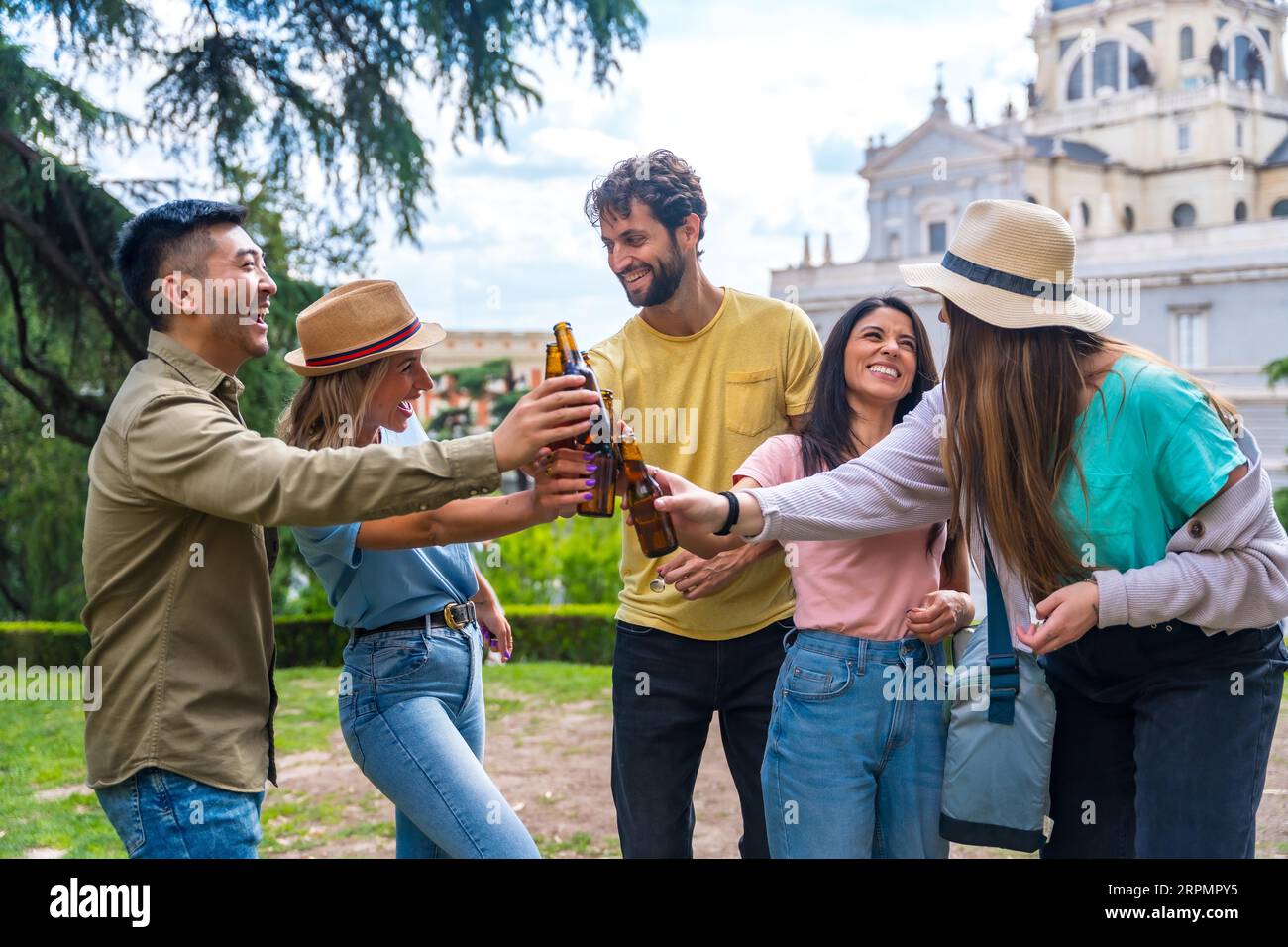 Gruppo multietnico di amici che festeggiano in un parco cittadino con birre. tostare con i biberon Foto Stock