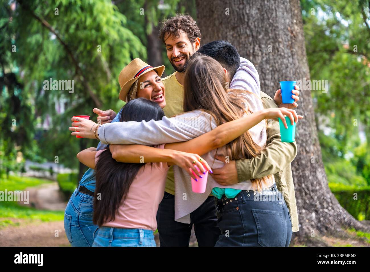 Gruppo multietnico di festa di compleanno nel parco cittadino abbracciato in un simbolo di amicizia per sempre Foto Stock