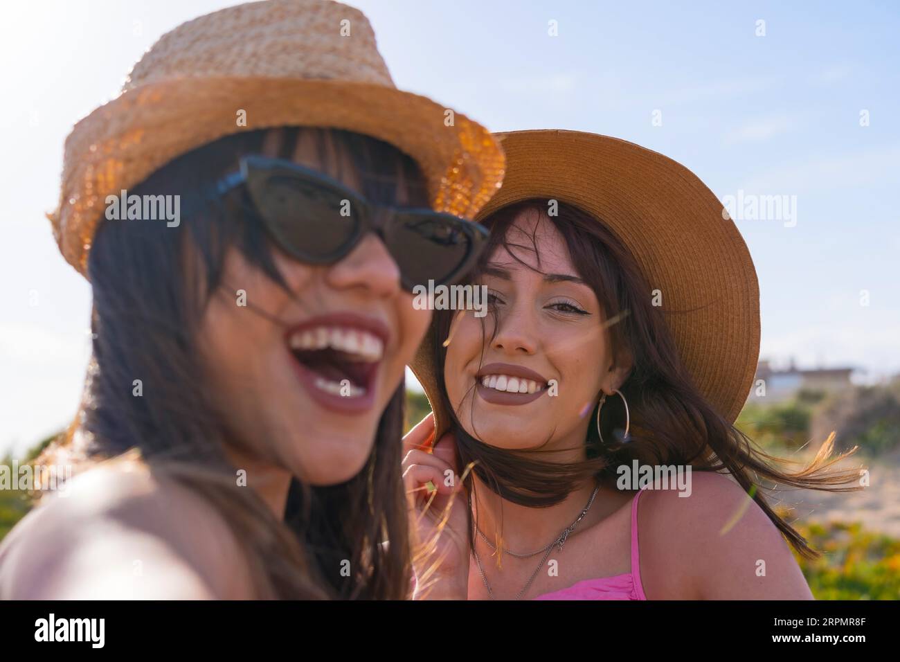 Primo piano di donne amiche con cappello in vacanza in spiaggia scattando un selfie con il telefono sorridente Foto Stock