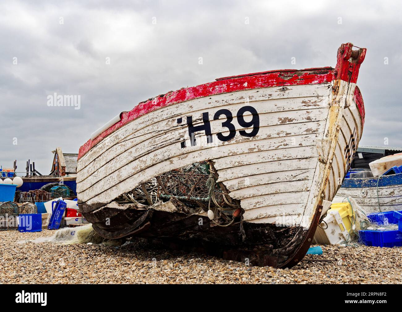 Barca fishihg abbandonata e danneggiata che marcisce sulla spiaggia di ciottoli di Aldeburgh, il Suffolk offre uno sfondo pittoresco ma triste a questa parte della città. Foto Stock