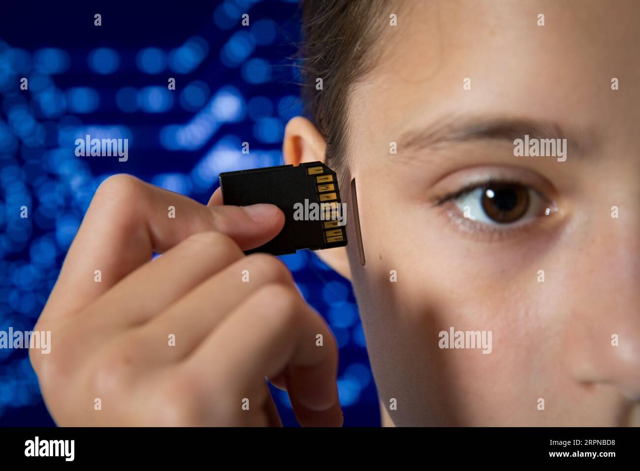 Ragazza adolescente che collega la scheda di memoria SD nello slot della sua testa. Intelligenza artificiale, dipendenza tecnologica e informatica, robotica, aggiornamento della memoria, controllo mentale, computing Foto Stock