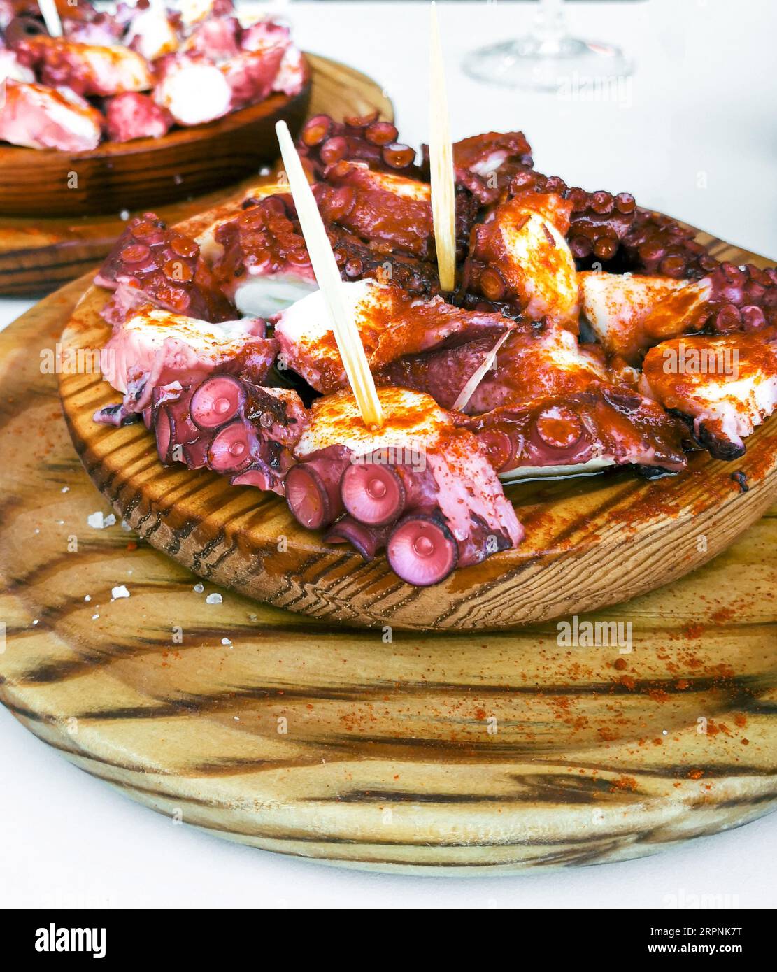 Deliziosi piatti in legno di stile galiziano polipo cotti con peperoncino e olio di oliva. Pulpo a la gallega Foto Stock