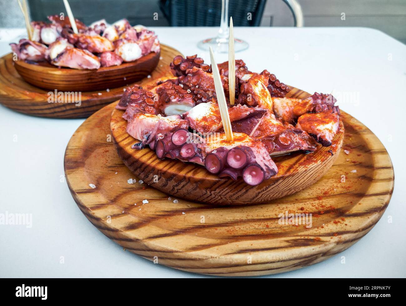 Deliziosi piatti in legno di stile galiziano polipo cotti con peperoncino e olio di oliva. Pulpo a la gallega Foto Stock