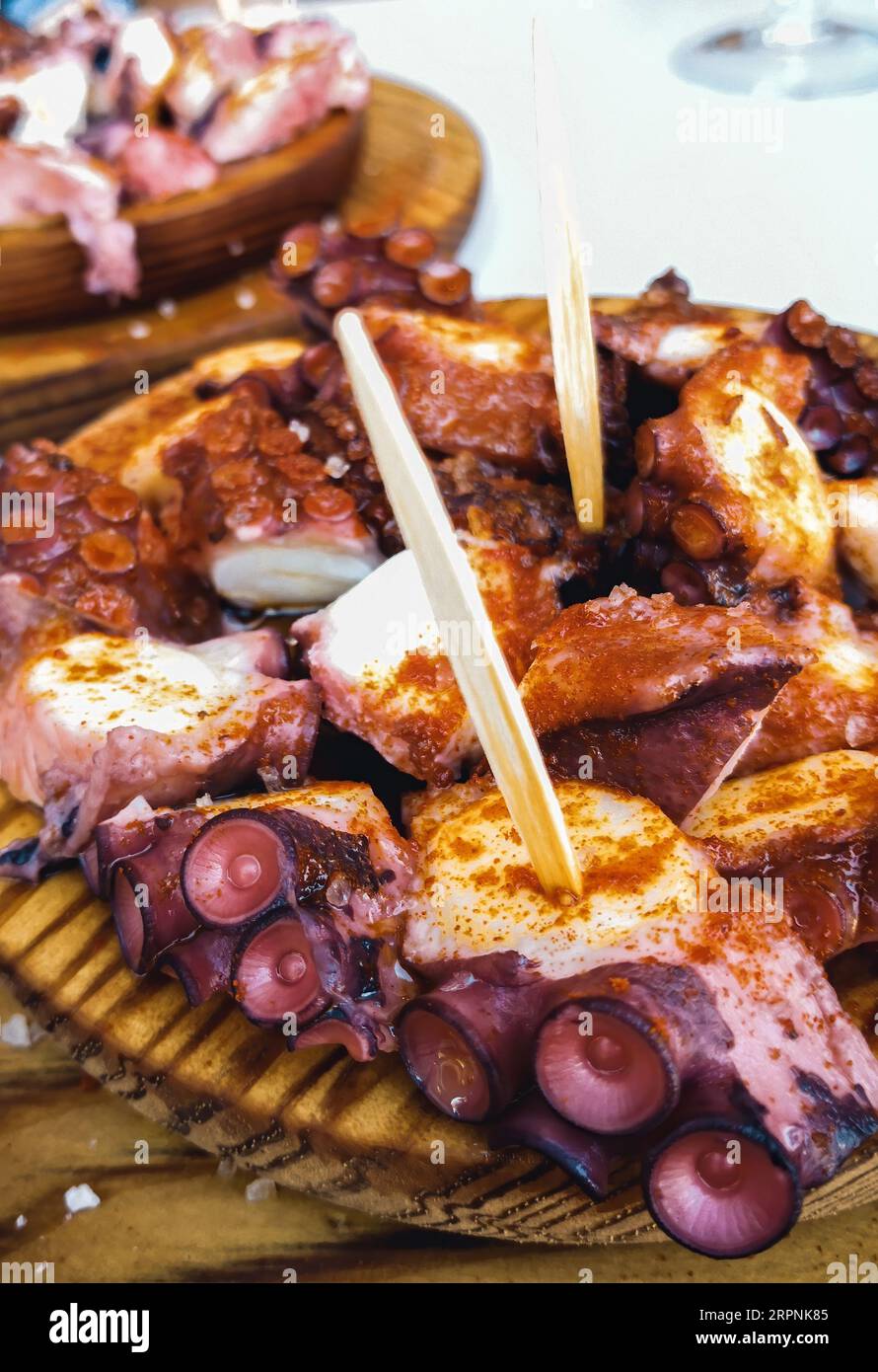 Deliziosi piatti in legno di stile galiziano polipo cotti con peperoncino e olio di oliva. Pulpo a la gallega Foto Stock