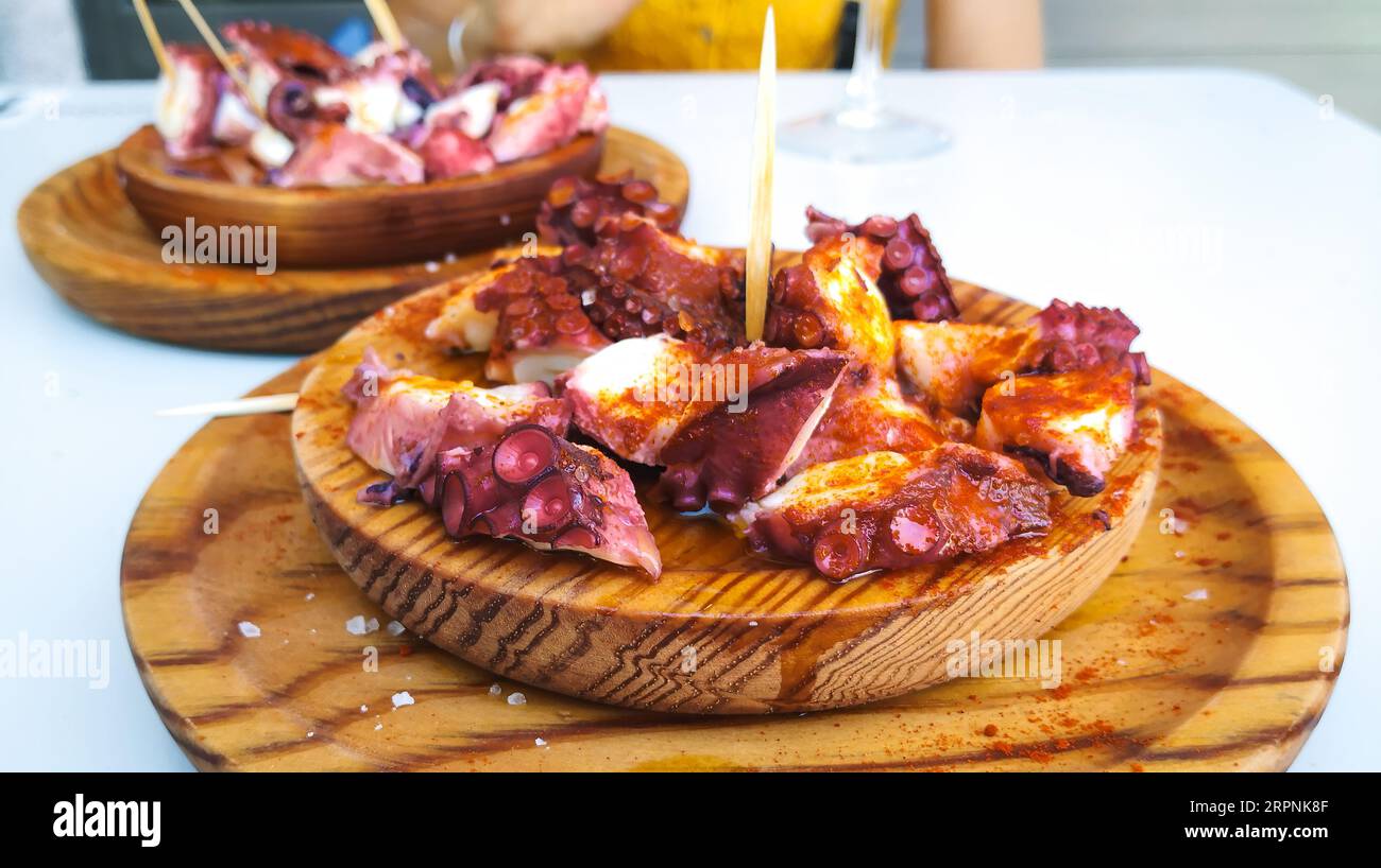 Deliziosi piatti in legno di stile galiziano polipo cotti con peperoncino e olio di oliva. Pulpo a la gallega Foto Stock