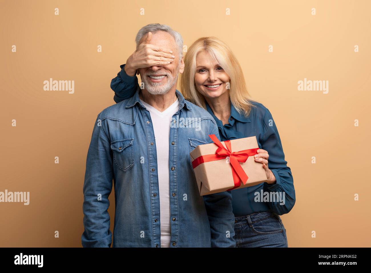 Bella donna anziana amorevole che fa una sorpresa di compleanno per suo marito Foto Stock