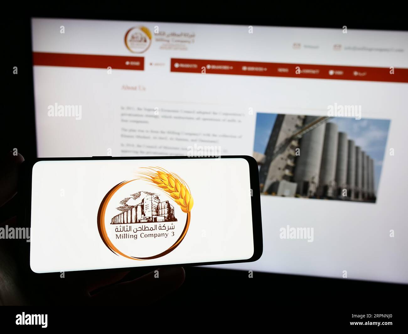 Persona che possiede uno smartphone con il logo dell'azienda saudita Milling Company 3 (MC3) sullo schermo davanti al sito Web. Concentrarsi sul display del telefono. Foto Stock