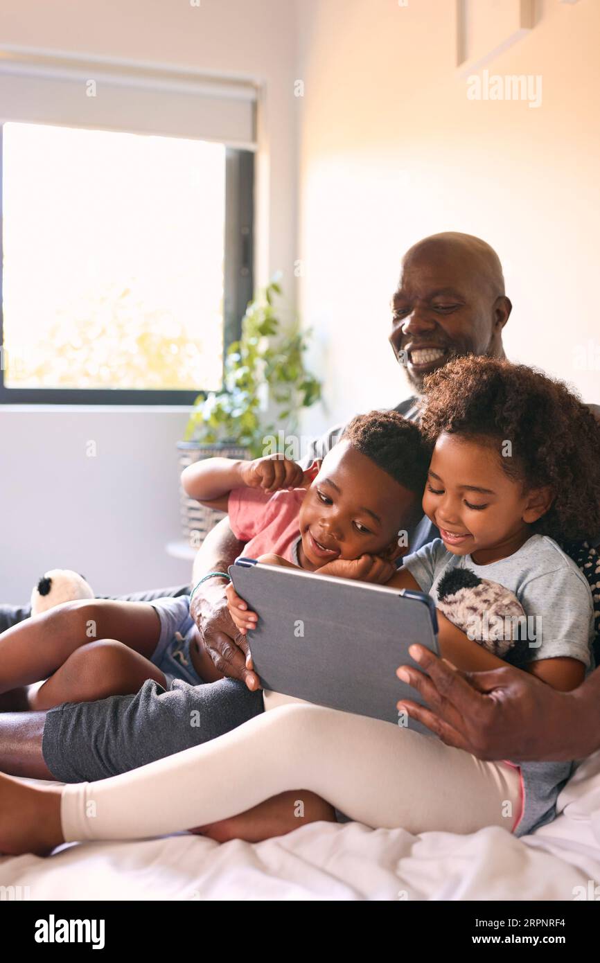 Nonno e nipoti con il tablet digitale che tira volti divertenti per Selfie a casa Foto Stock