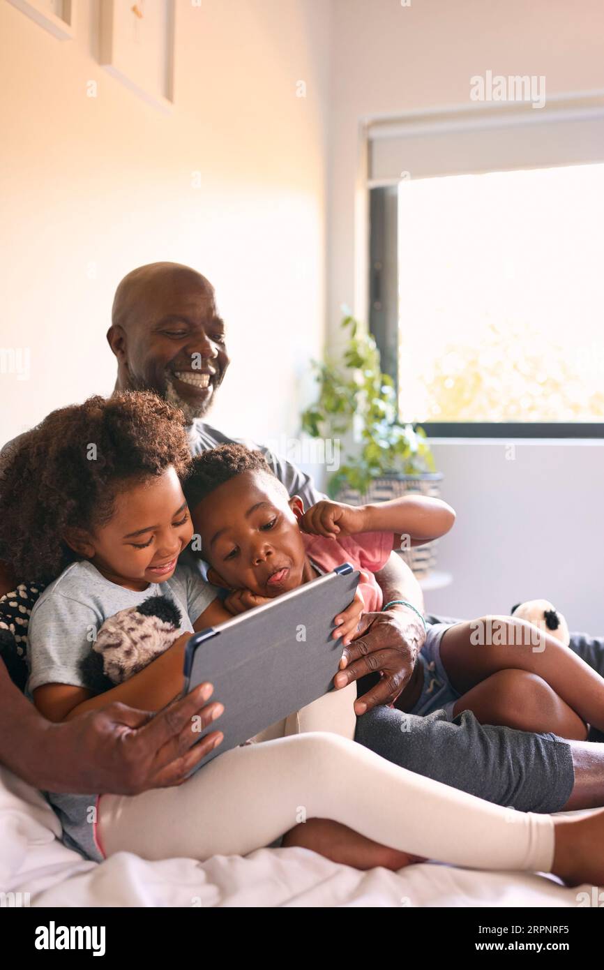Nonno e nipoti con il tablet digitale che tira volti divertenti per Selfie a casa Foto Stock