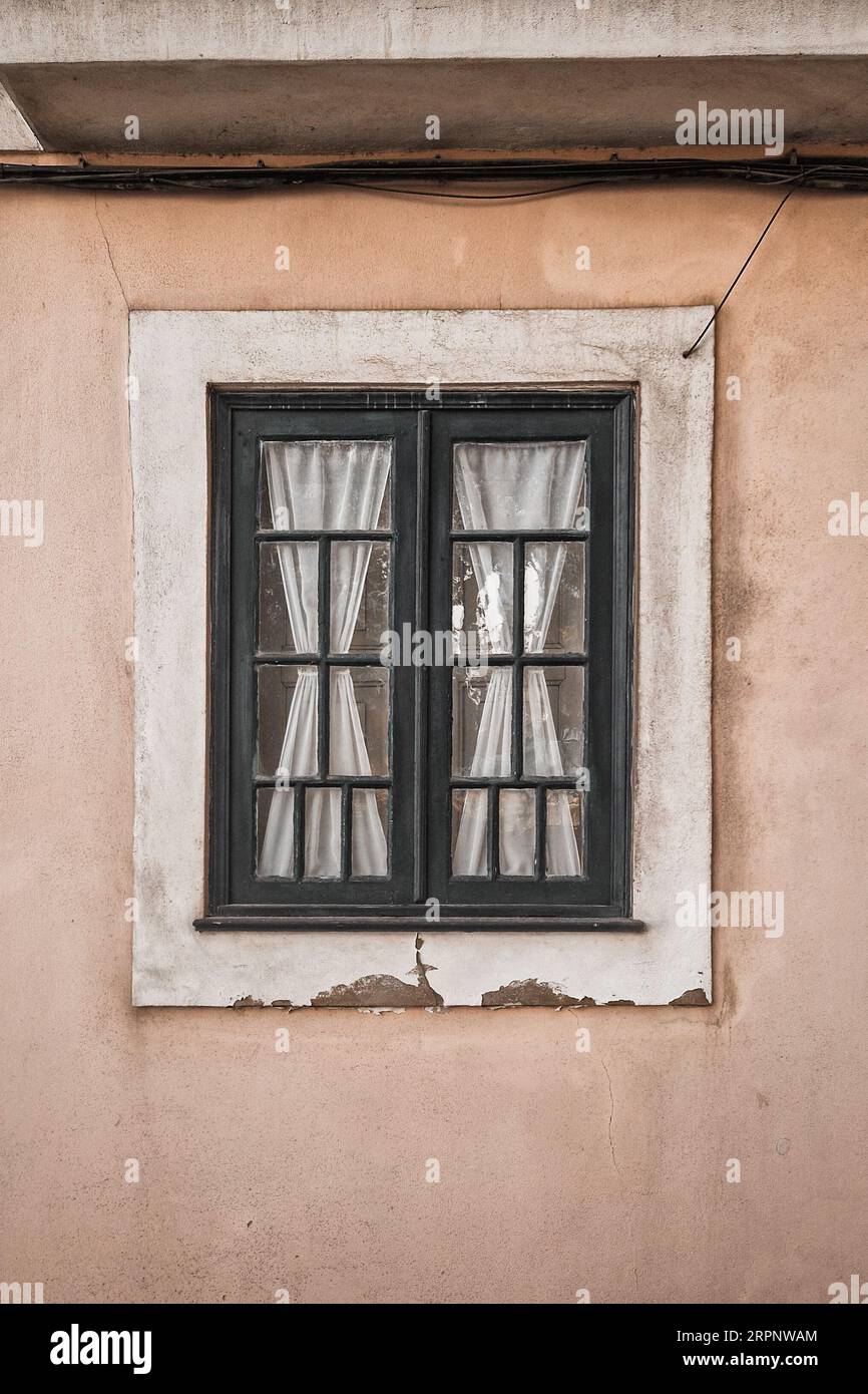 Primo piano della vecchia finestra tradizionale portoghese con bellissime tende tessili bianche Foto Stock