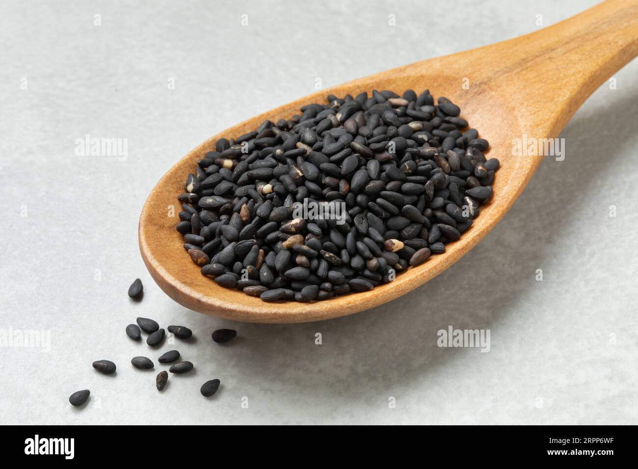 Cucchiaio di legno con semi di sesamo arrosto nero da vicino Foto Stock