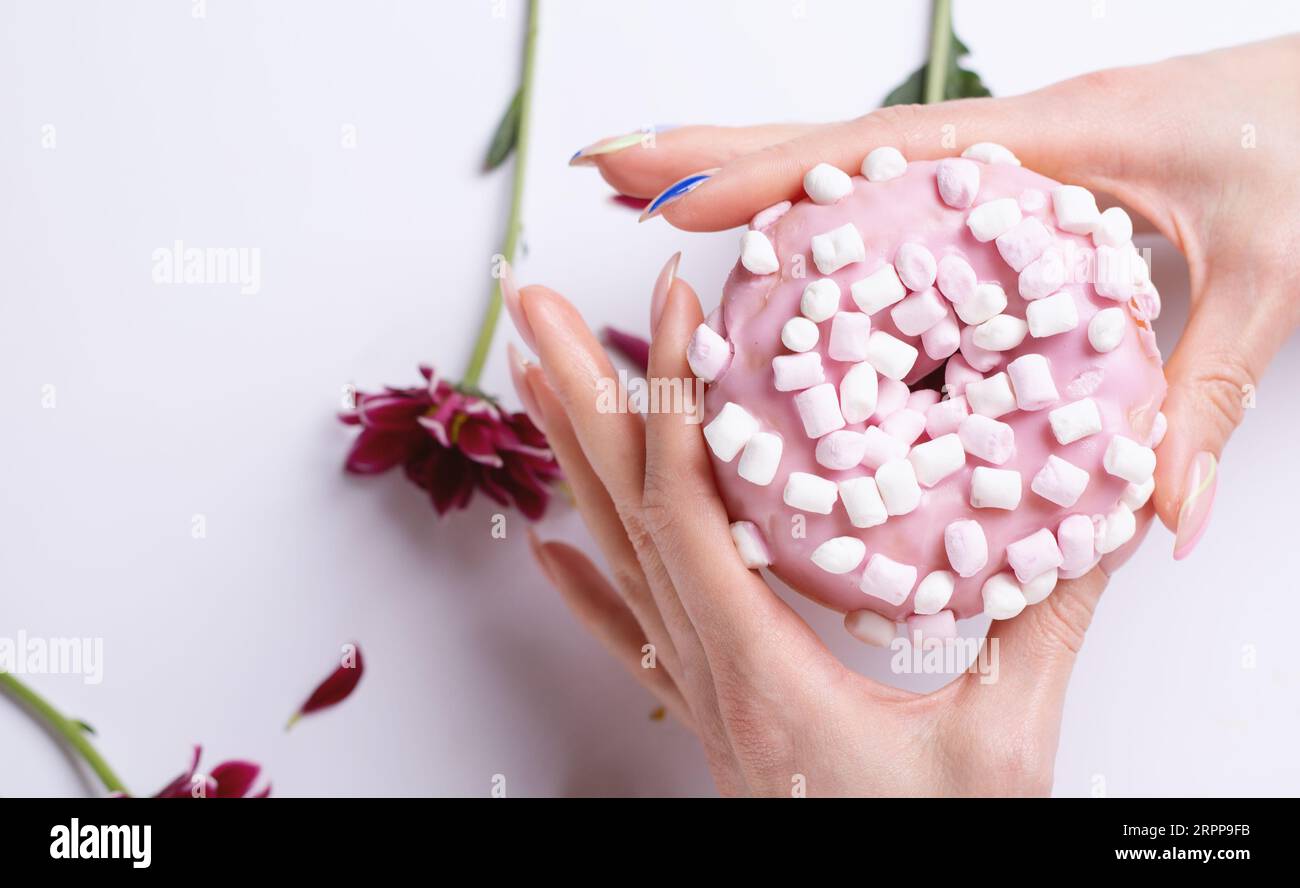 Ciambella rosa e mano femminile con manicure Foto Stock