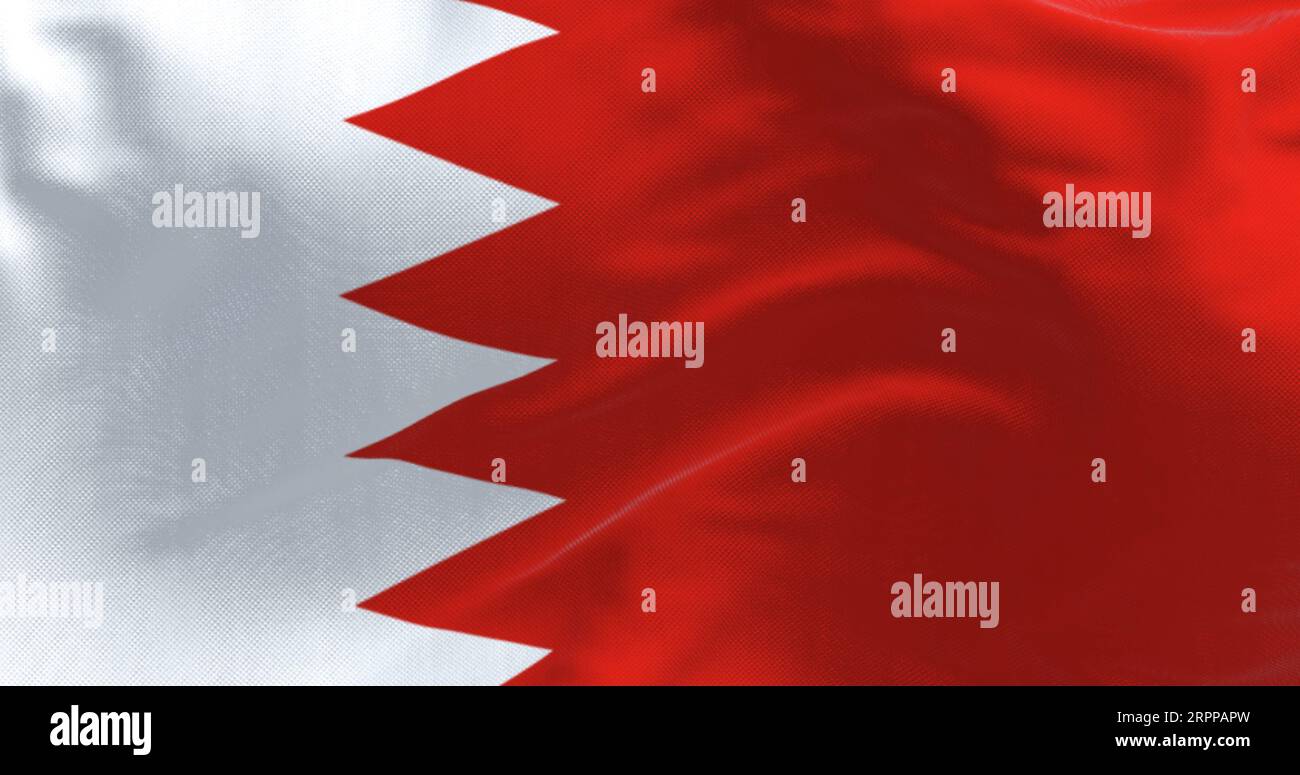 Primo piano della bandiera nazionale del Bahrein che sventola. Banda bianca a sinistra e area rossa a destra, separate da cinque triangoli che formano una linea seghettata. Foto Stock