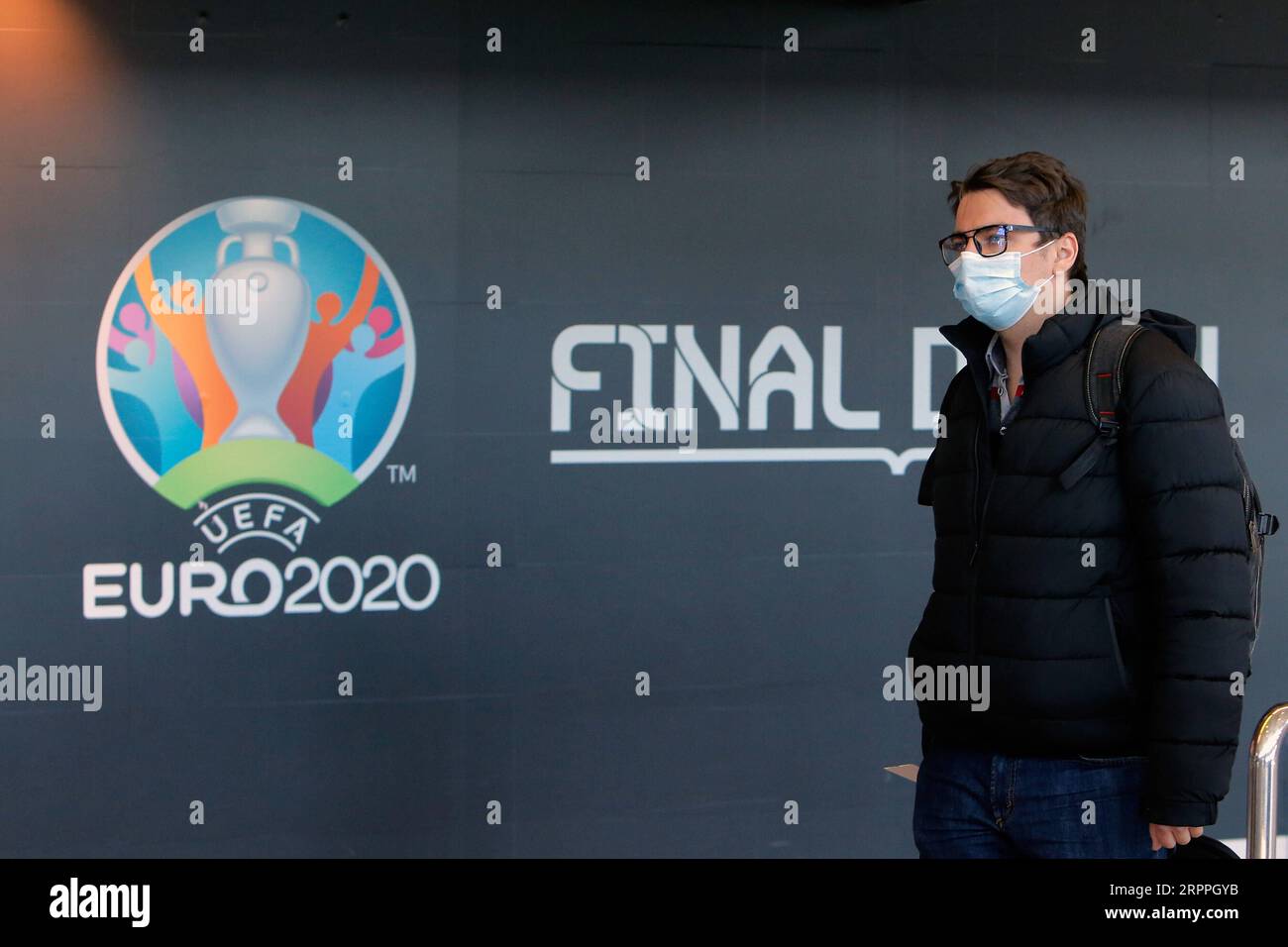 200318 - BUCAREST, 18 marzo 2020 Xinhua - Un uomo che indossa una maschera passa davanti a un logo del Campionato europeo di calcio EURO 2020 esposto su un muro all'aeroporto internazionale Henri Coanda di Bucarest, in Romania, 17 marzo 2020. L'organo di governo europeo del calcio UEFA ha deciso di rinviare il Campionato europeo di calcio di quest'estate al 2021 a causa dell'epidemia di coronavirus. Il presidente rumeno Klaus Iohannis ha annunciato che il paese entrerà in uno stato di emergenza a partire dal 16 marzo, nel tentativo di garantire che il governo utilizzi tutte le risorse per combattere l'epidemia di COVID-19. Foto di Cristian C. Foto Stock