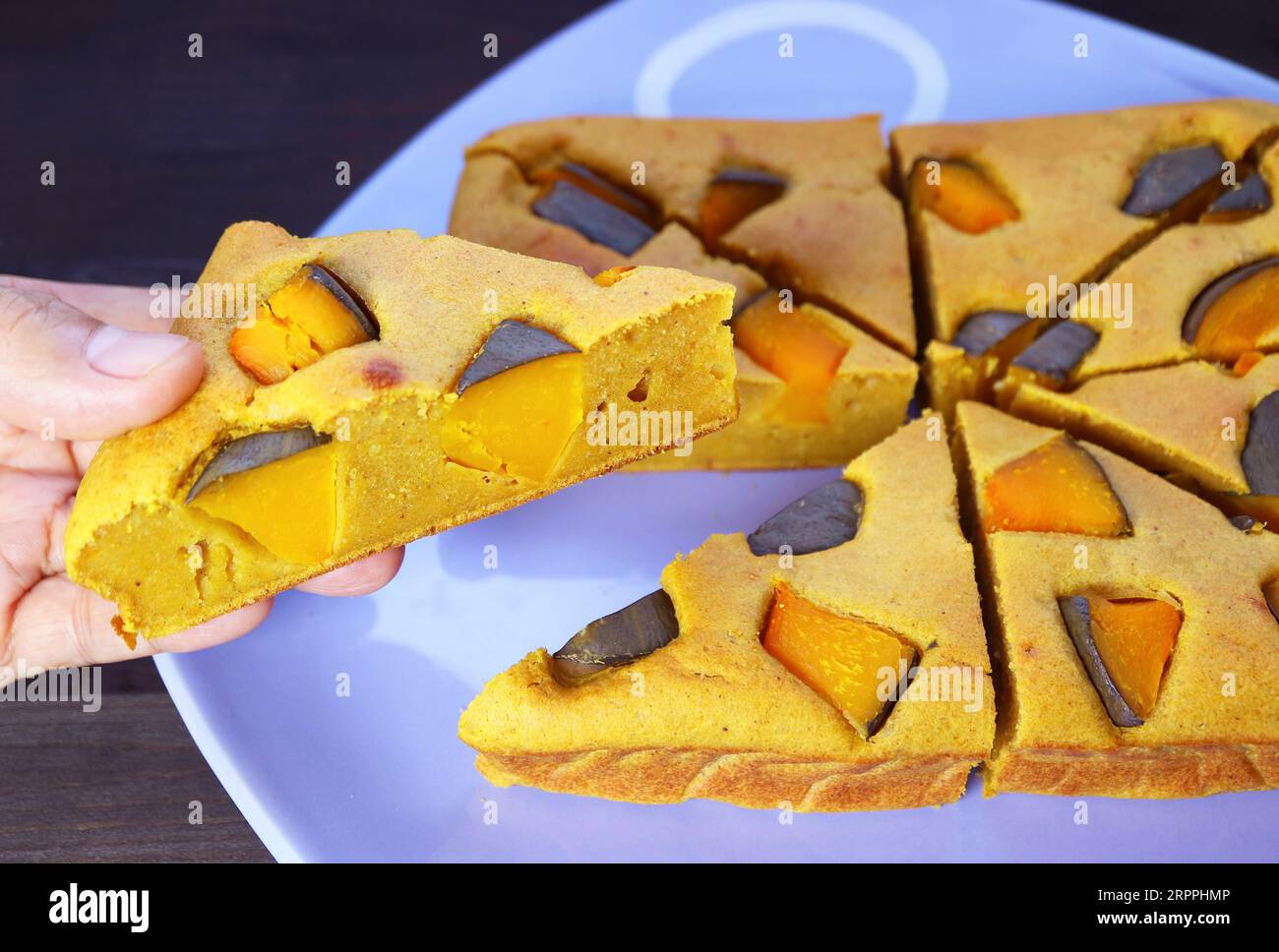 Primo piano sulla raccolta a mano di una fetta di torta di zucca appena sfornata Foto Stock