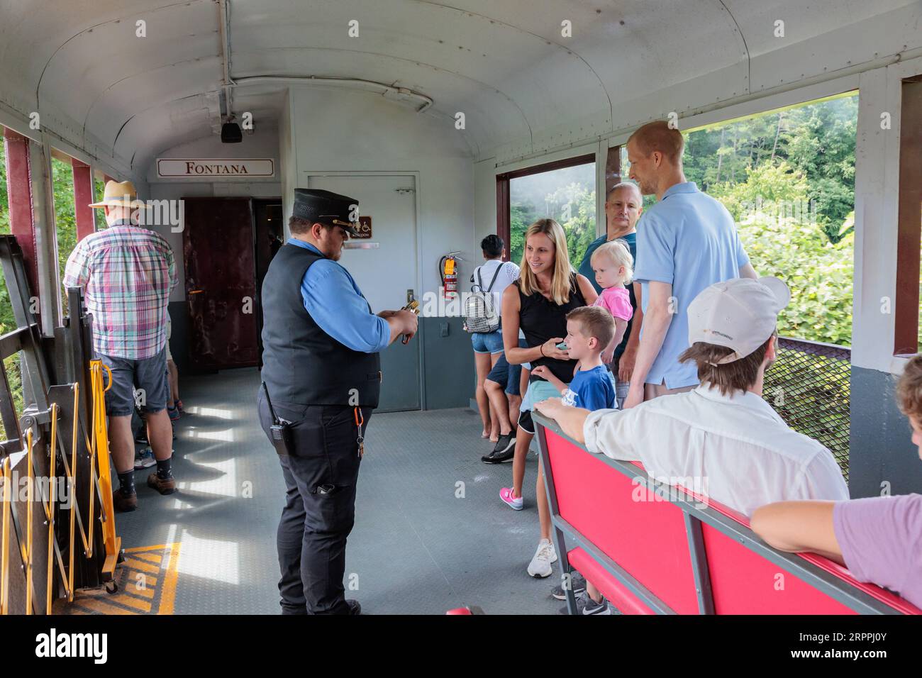 La giovane famiglia guarda un collezionista di biglietti prendere a pugni i loro biglietti ricordo durante l'escursione alla ferrovia delle Great Smoky Mountains da Bryson City, North Carolina Foto Stock