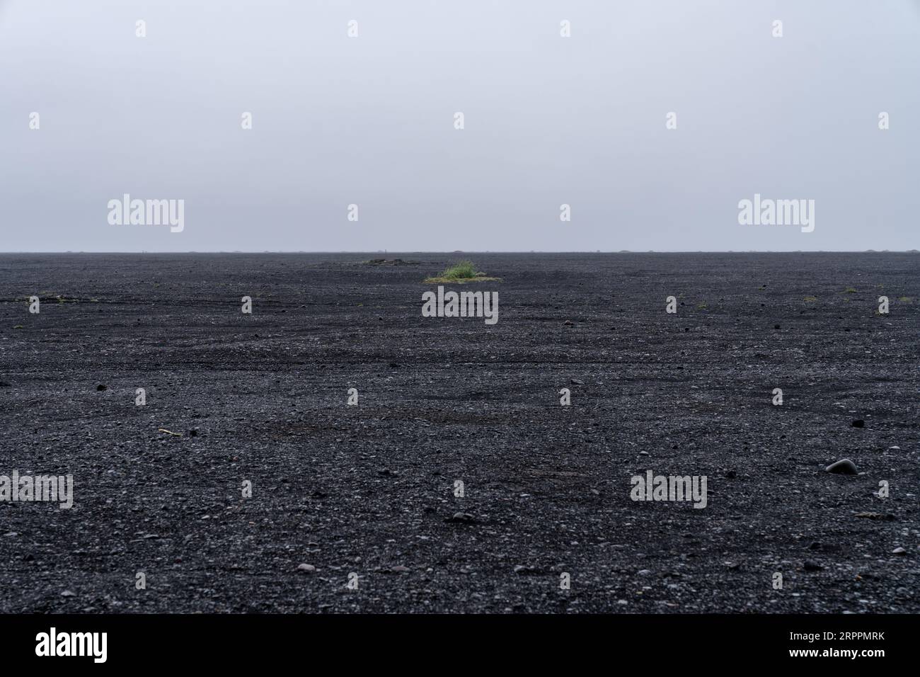 Spiaggia rocciosa, di sabbia nera e di roccia ghiaiosa in Islanda. Paesaggio minimalista a Hjörleifshöfði, niente persone Foto Stock