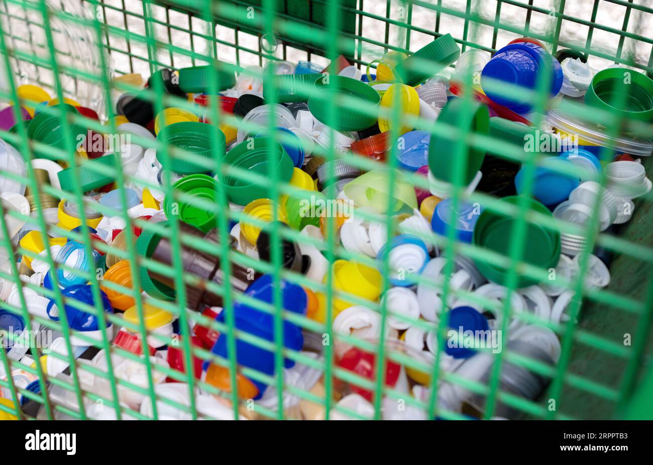 Contenitore per riciclaggio urbano pieno di tappi per bottiglie in plastica. Ambiente e concetto globale Foto Stock