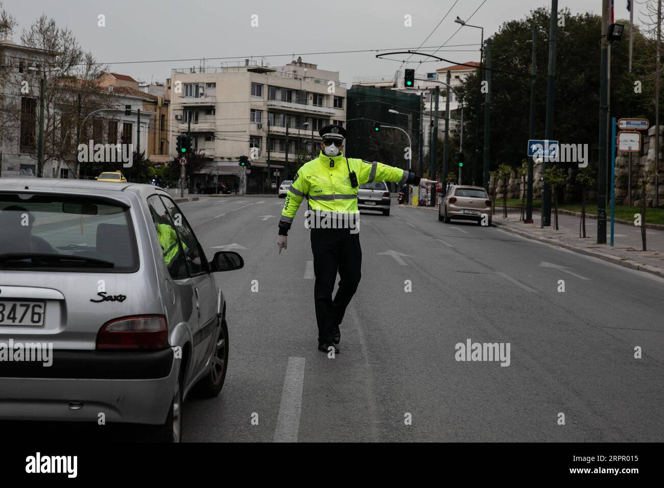 200323 -- ATENE, 23 marzo 2020 -- Un poliziotto ferma un'auto per controllare i documenti ad Atene, in Grecia, il 23 marzo 2020. Le strade cittadine in tutta la Grecia sono state deserte quando il governo ha lanciato lunedì un blocco nazionale di 14 giorni nel tentativo di contenere l'ulteriore diffusione della COVID-19. Finora la Grecia ha registrato 17 decessi legati alla COVID-19, rispetto ai 15 segnalati un giorno prima e a 71 nuovi casi confermati, portando il totale a 695. Foto di /Xinhua GRECIA- ATENE-COVID19-LOCKDOWN LEFTERISxPARTSALIS PUBLICATIONxNOTxINxCHN Foto Stock