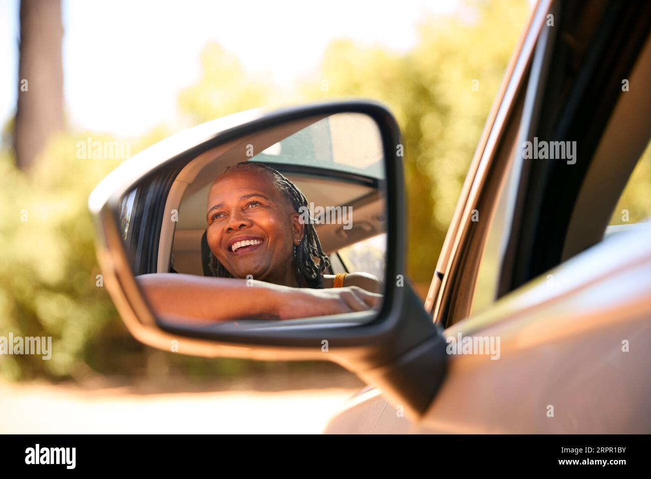 Autista anziano sorridente che guarda fuori dal finestrino dell'auto e che si gode una gita di un giorno in auto Foto Stock