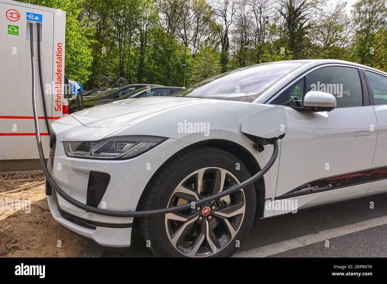 AACHEN, NRW, Germania - 23 Aprile 2019: auto elettrica, Jaguar, collegato con un cavo di alimentazione a un pubblico di carica elettrica colonna per la ricarica. Foto Stock