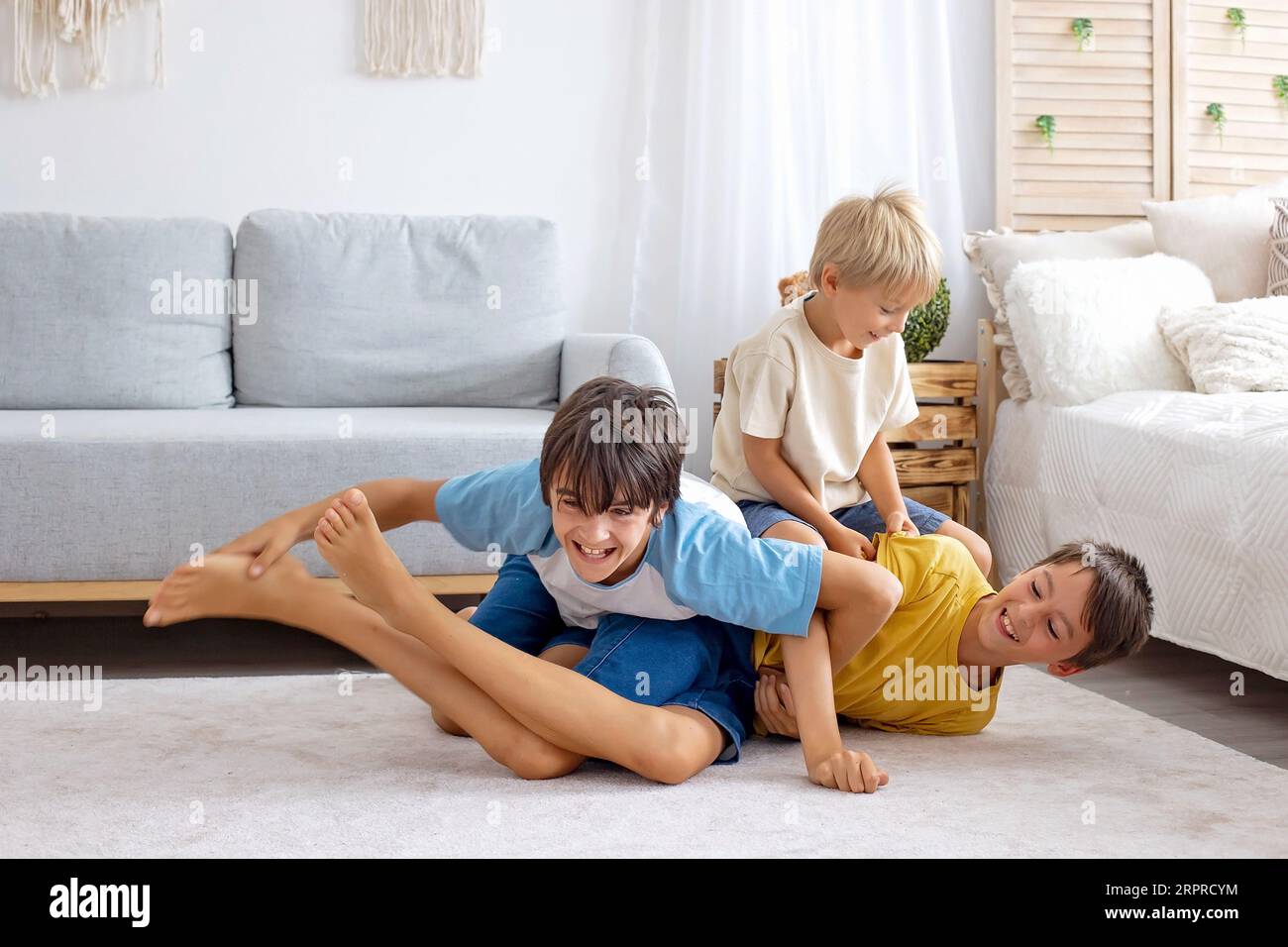 Bambini felici e positivi, solletico in piedi, divertimento insieme, ragazzi fratelli a casa che trascorrono una meravigliosa giornata di gioia insieme Foto Stock