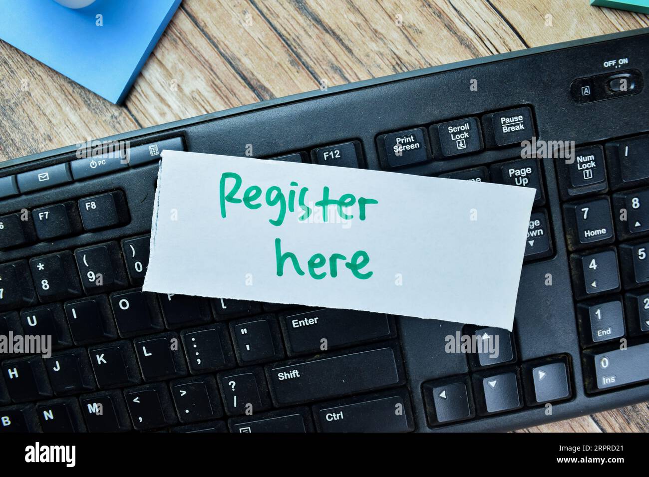 Concetto di registrazione qui scrivere su appunti adesivi con parole chiave isolate su tavola di legno. Foto Stock