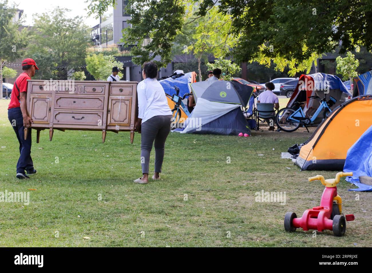 Un paio di richiedenti asilo prendono alcuni mobili lasciati sul marciapiede per il ritiro dei rifiuti mentre occupano un rifugio temporaneo in uno spazio verde adiacente alla stazione di polizia del 12th District sul vicino West Side di Chicago il 5 settembre 2023. Circa la metà dei 13, 500 migranti arrivati a Chicago lo scorso anno sono ancora in attesa di essere collocati in alloggi temporanei mentre la città lotta per trovare un rifugio. (Foto di: Alexandra Buxbaum/Sipa USA) credito: SIPA USA/Alamy Live News Foto Stock