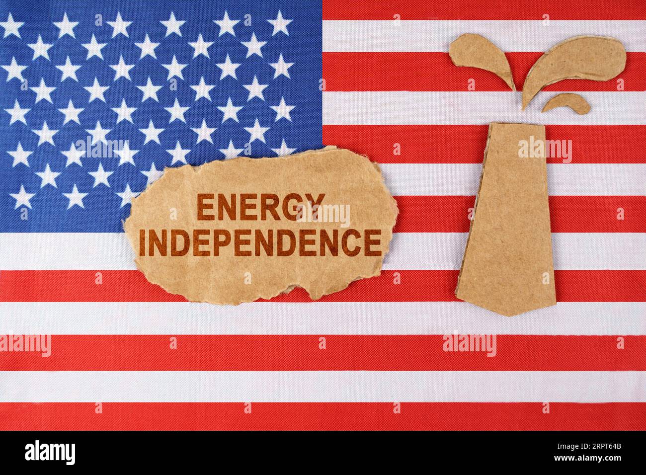 Sulla bandiera degli Stati Uniti c'è una piattaforma petrolifera tagliata in cartone e un cartello con l'iscrizione "indipendenza energetica". Foto Stock