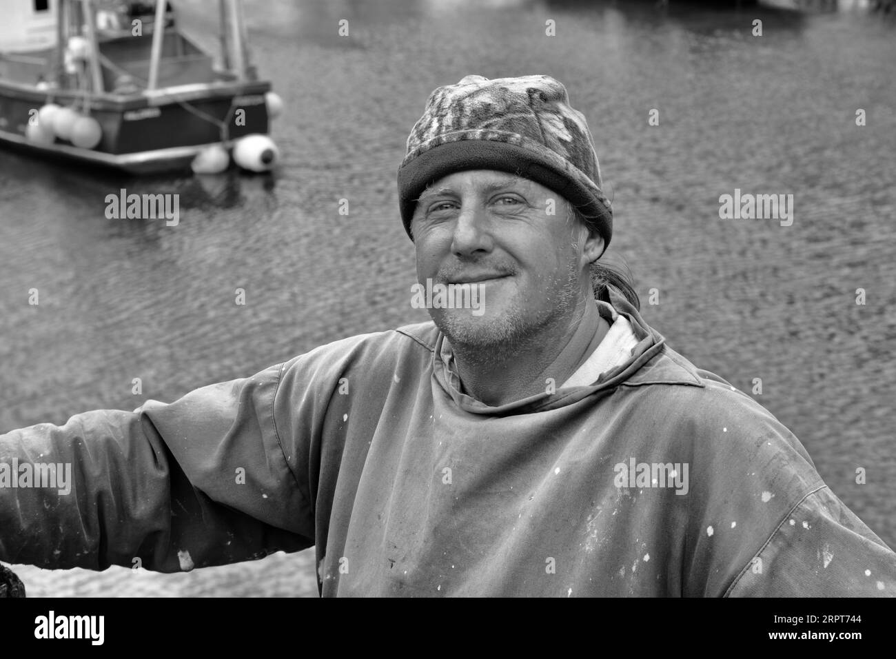 Immagine in bianco e nero di un amichevole pescatore della cornovaglia che ha caricato il suo pescato sul molo ed è soddisfatto del suo lavoro per tutta la giornata. Foto Stock