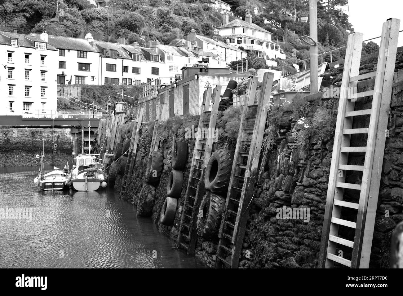 Le pareti del porto di Polperro hanno scale, pneumatici e scalini per aiutare i pescatori ad accedere al molo sopra in bassa marea. Foto Stock