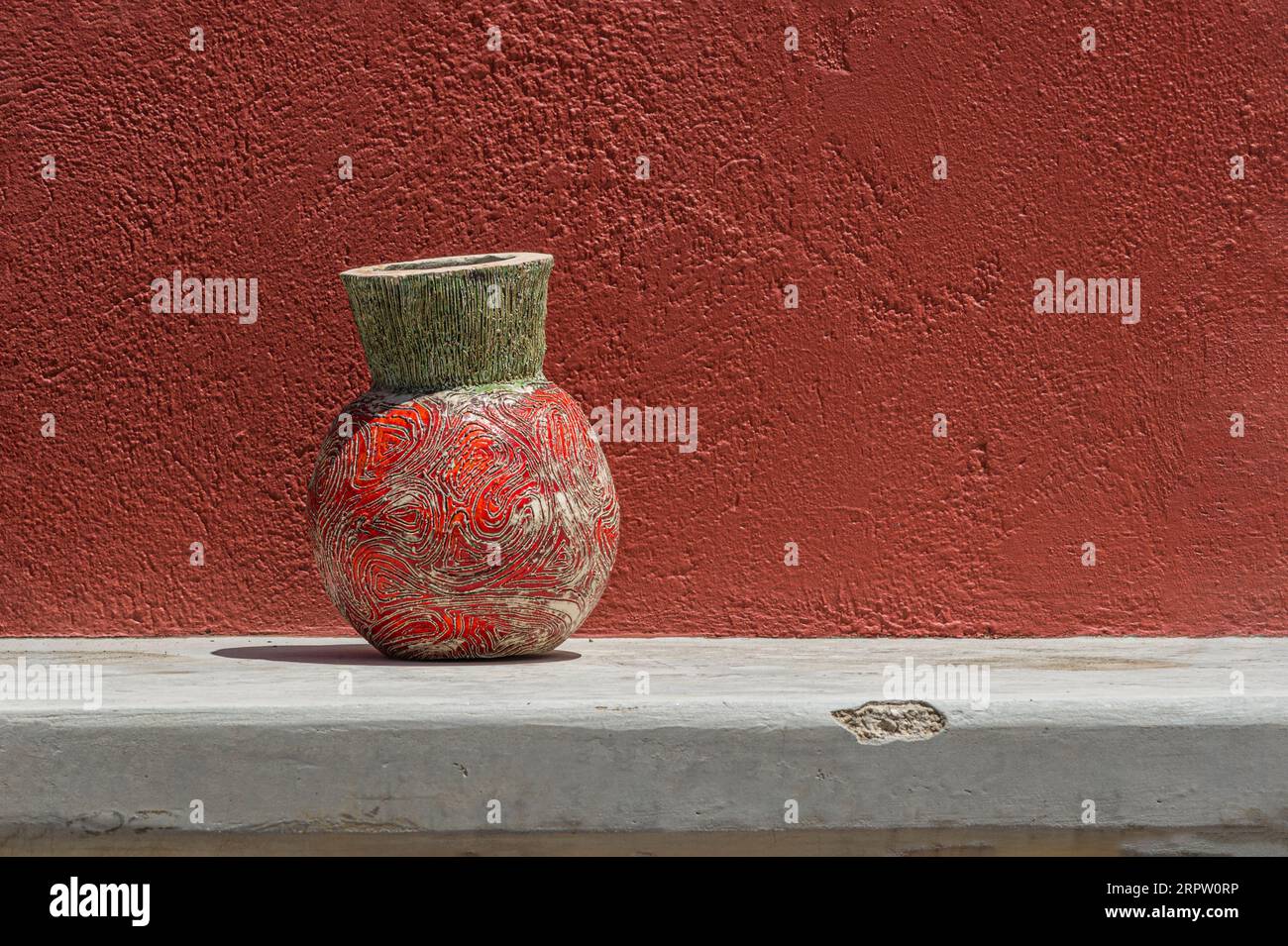 Ceramiche di argilla rotonde contro la parete rossa alla luce del sole Foto Stock
