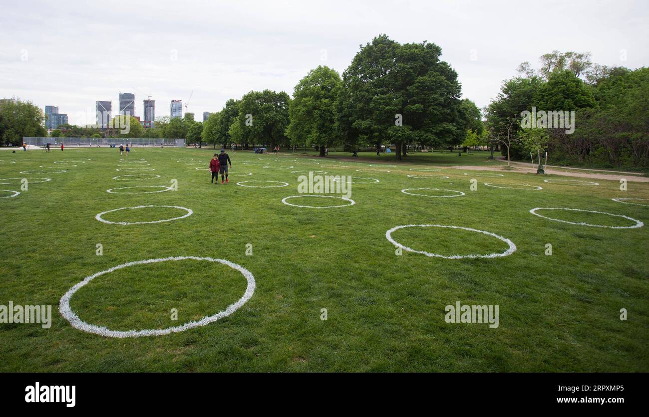 200528 -- TORONTO, 28 maggio 2020 -- la gente cammina attraverso cerchi bianchi dipinti sull'erba al Trinity Bellwoods Park di Toronto, Canada, il 28 maggio 2020. La città di Toronto ha dipinto cerchi sull'erba al Trinity Bellwoods Park come progetto pilota giovedì per incoraggiare le persone in distanziamento fisico durante l'epidemia di COVID-19. Foto di /Xinhua CANADA-TORONTO-COVID-19-PARK-PHYSICAL DISTANCING-CIRCLES ZouxZheng PUBLICATIONxNOTxINxCHN Foto Stock