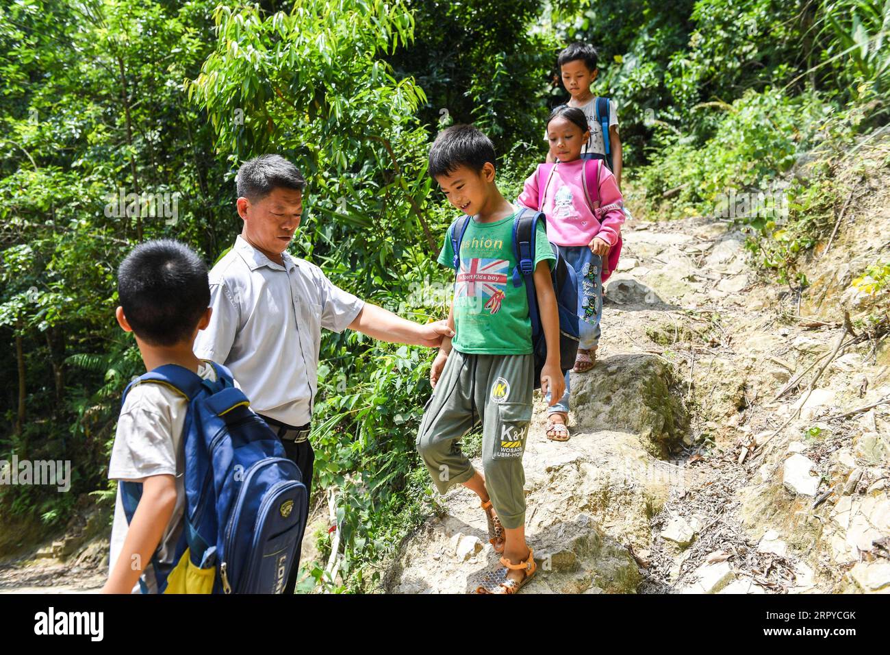200625 -- NINGMING, 25 giugno 2020 -- Jiao Shengding accompagna gli studenti dopo la scuola mentre tornano a casa nella città di Aidian della contea di Ningming, nella regione autonoma del Guangxi Zhuang della Cina meridionale, 23 giugno 2020. Jiao Shengding, 52 anni, è l'unico insegnante presso il sito di insegnamento del villaggio di Zhangji, che si trova al confine tra Cina e Vietnam. Dopo essersi diplomato presso la scuola professionale secondaria della contea nel 1990, Jiao ha scelto di essere un insegnante presso il villaggio di Zhangji e da allora ha insegnato lì per 30 anni. Negli ultimi tre decenni, ha insegnato più di 400 alunni, la maggior parte Foto Stock