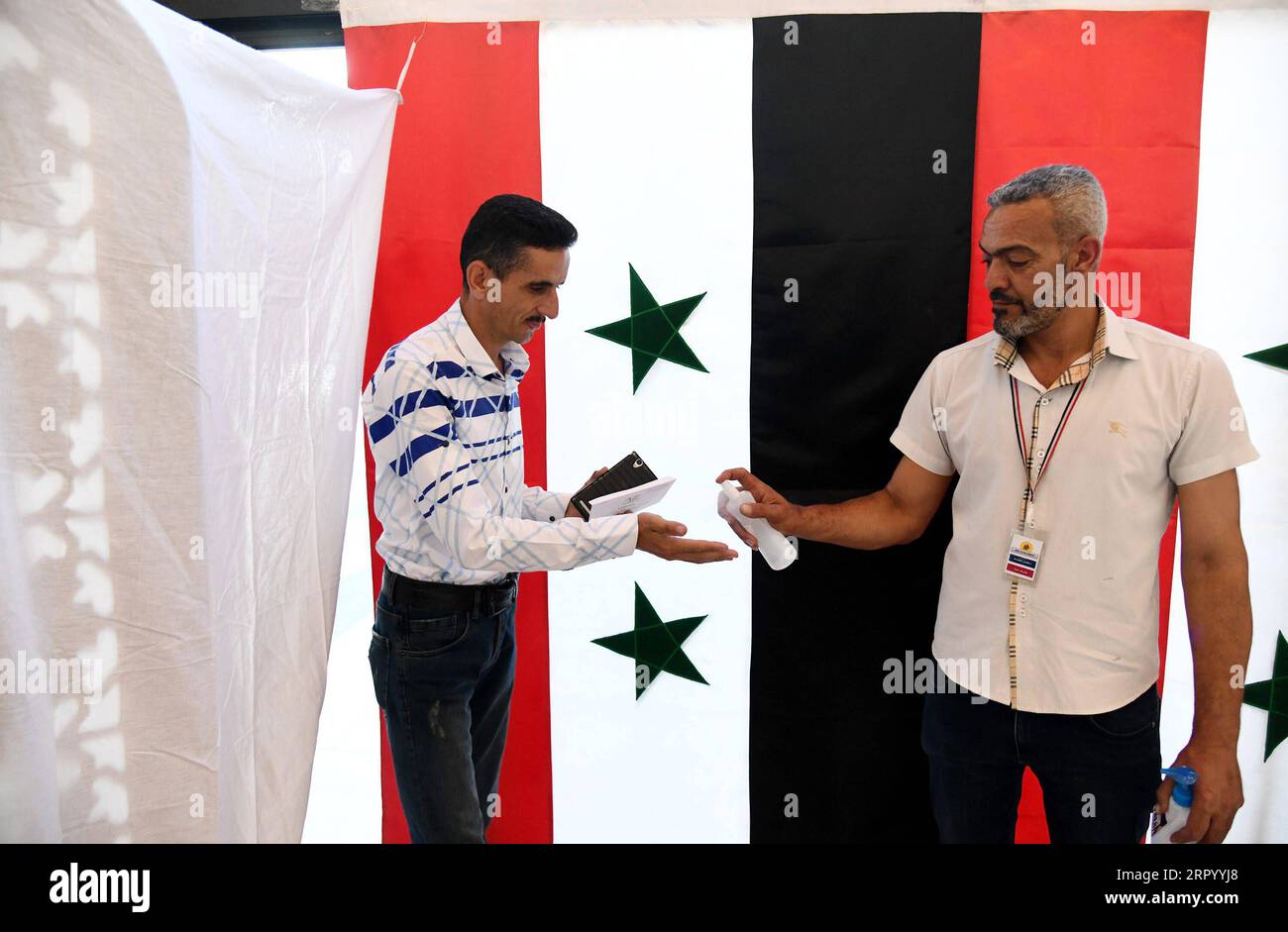 200719 -- DAMASCO, 19 luglio 2020 -- Un membro dello staff spruzza disinfettante sulla mano di un elettore durante le elezioni parlamentari a Damasco, capitale della Siria, il 19 luglio 2020. Le elezioni parlamentari in Siria sono iniziate domenica, le tre elezioni durante la guerra lunga più di nove anni, tra la partecipazione del presidente Bashar al-Assad e di sua moglie asma. Foto di /Xinhua SIRIA-DAMASCO-ELEZIONI PARLAMENTARI AmmarxSafarjalani PUBLICATIONxNOTxINxCHN Foto Stock