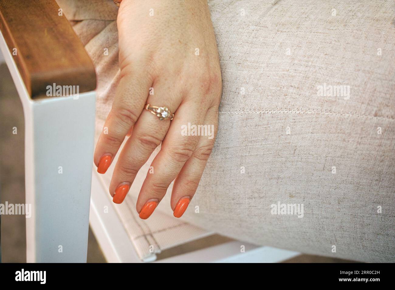 primo piano della mano femminile con anello dorato sul dito e manicure Foto Stock
