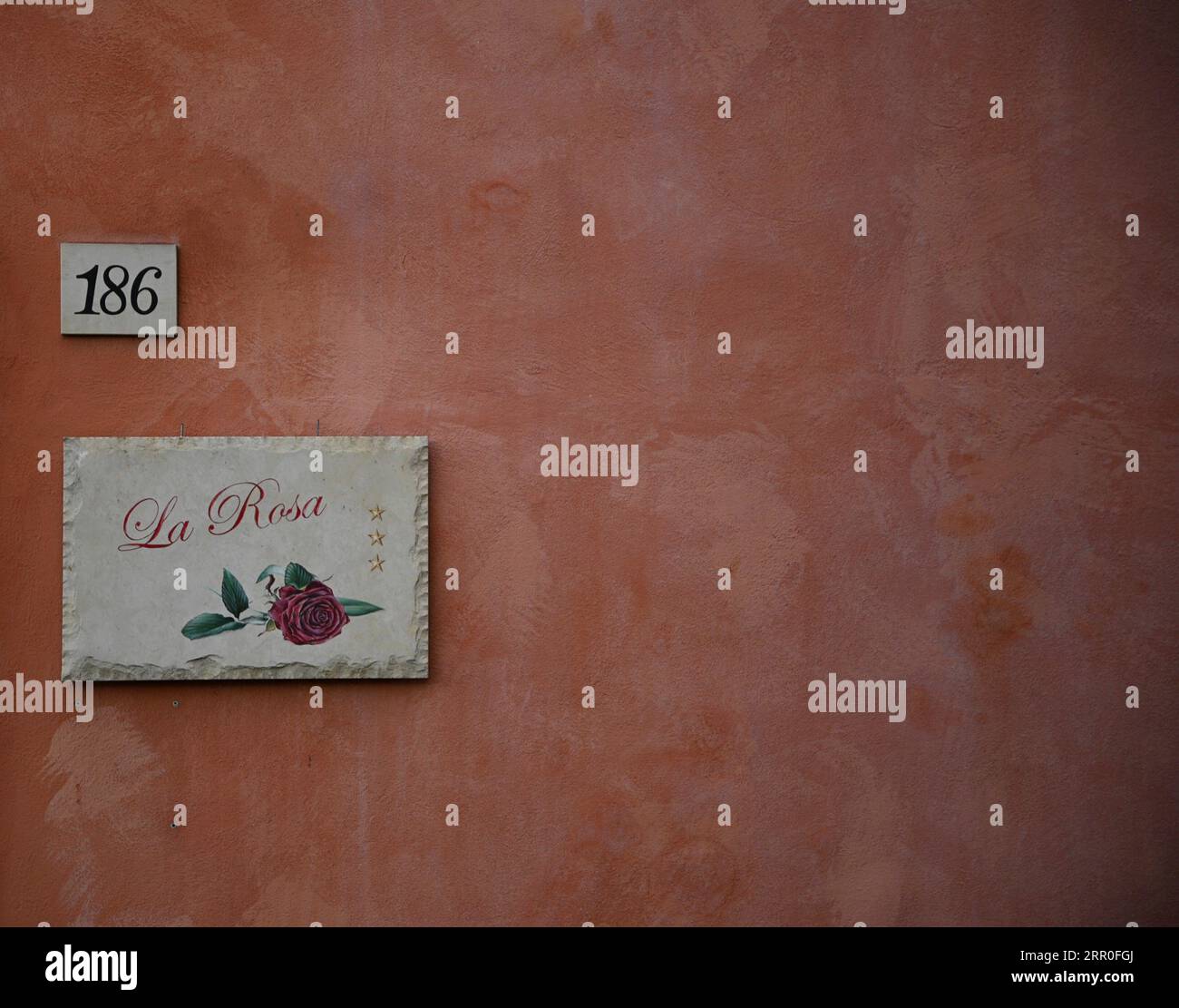 Antico segno dipinto a mano della casa vacanze "la Rosa" su una parete in stucco rosso veneziano a Ragusa Ibla Sicilia, Italia. Foto Stock